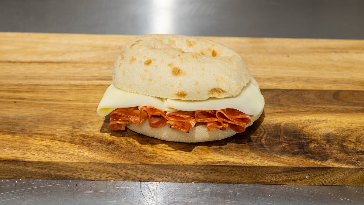 A Rose's Deli hot salami and provolone roll on the wooden counter
